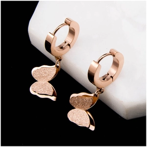 Boucles d'oreilles créoles papillon or rose mat sur socle en marbre blanc