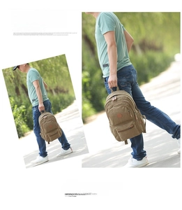 Detail of khaki canvas backpack featuring multi-pocket design and leather logo patch