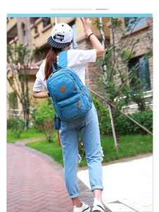 Outdoor back view of a blue canvas backpack featuring multiple zipper compartments