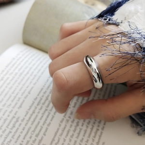 Detailed view of an irregular polished silver 925 ring worn against a book background