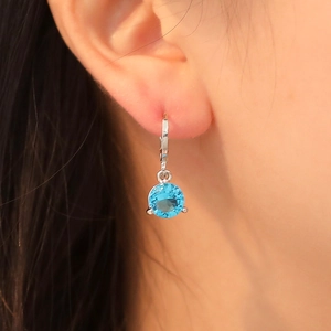 Boucle d'oreille minimaliste en argent avec zircon bleu portée par un mannequin