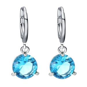 Détail de boucles d'oreilles argentées avec zircone bleue ronde et serti à griffes