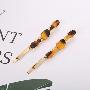 Golden metal hair clips set with tortoise shell acrylic decorations on elegant background