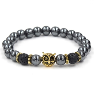 Detailed close-up of golden owl charm and black lava beads on a stone bracelet