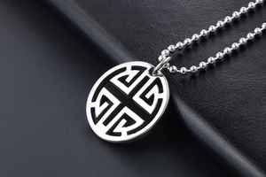 Macro shot of silver hollow circular pendant with stylized character on dark leather