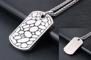 Detailed close-up of a silver pebble-textured military tag pendant on a curb chain