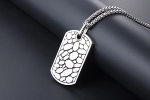 Macro shot of silver titanium dog tag necklace with embossed pebble texture and woven chain