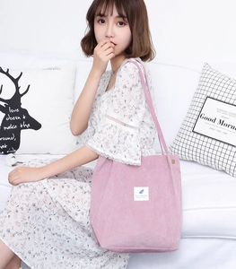 Detail of pink corduroy tote bag featuring feather embroidery and metal magnetic closure