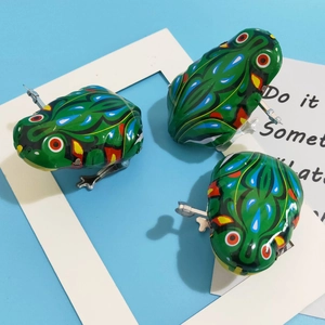 Detailed close-up of three vintage wind-up green tin frogs with colorful patterns