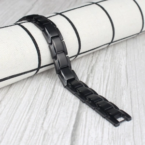 Detail of black titanium steel magnetic health bracelet links on textured fabric