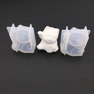 Detail view showing translucent silicone Maneki Neko molds with a finished white plaster cat