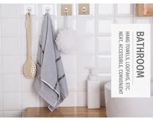 Adhesive wall hooks in transparent and gold style holding bath towels and shower brushes