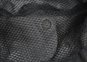 Détail du tissu en maille noire respirante et de l'œillet d'aération sur le chapeau