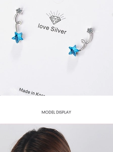 Detail view of blue star crystal stud earrings on jewelry card and model ear lobe