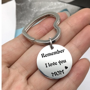 Close-up of hand holding a silver stainless steel heart ring keychain with MOM engraving