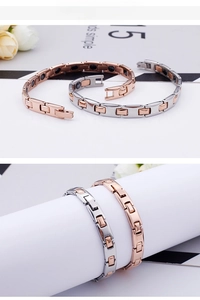Detail of rose gold and silver magnetic therapy bracelets on a cylindrical display stand
