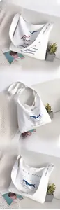 Detail of white canvas crossbody bag with blue whale and wave prints for daily style