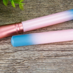 Close-up of pink-blue gradient makeup brush handles with rose gold ferrules on wood