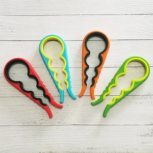 Set of four colorful non-slip jar openers in red, blue, orange, and green on wood