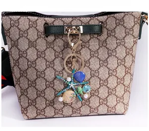 Détail d'un pendentif étoile de mer et perle sur un sac seau vintage à monogramme