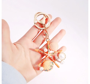 Détail de porte-clés étoile de mer orange avec coquillages, perles et cristaux