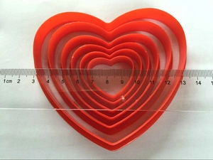 Set of six red heart-shaped plastic cookie cutters shown with measuring ruler for size