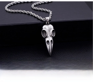 Macro shot of gothic raven skull pendant with vintage finish on black leather background