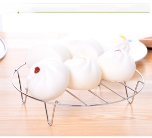 Close-up of stainless steel steaming rack holding traditional buns on wooden table