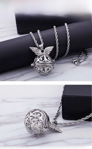 Detail of silver hollow cage pendant with angel wings on marble display stand