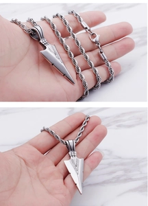 Gros plan d'un pendentif flèche en argent avec texture géométrique sur une chaîne torsadée