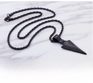 Détail d'un pendentif en forme de pointe de flèche noir mat sur une chaîne de corde torsadée