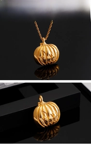 Vue macro du pendentif citrouille en acier doré avec détails de Jack-o'-lantern