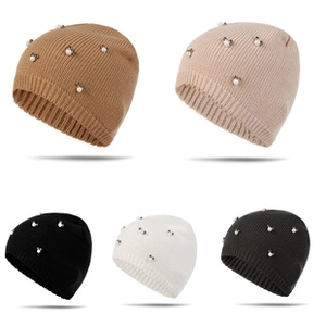 Détail de cinq bonnets en maille colorés ornés de motifs de flocons en perles nacrées