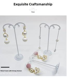 Detailed view of elegant pearl drop earrings and gold cat charms on display stands