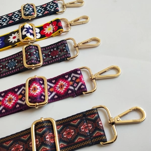 Detail of adjustable woven bag straps with ethnic patterns and gold metal buckles
