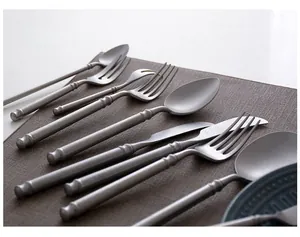 Detail of vintage matte silver stainless steel cutlery set on a textured dark placemat