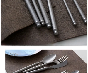 Macro detail of matte stainless steel cutlery with retro cylindrical handles on a dark placemat