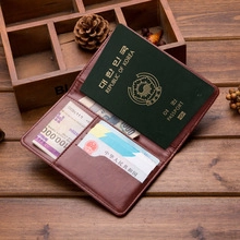 Detail of dark brown leather passport holder with multiple slots on a rustic wooden desk