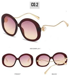 Detail of burgundy oval sunglasses with golden wavy temples and white pearl accents