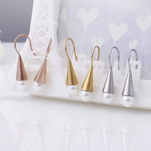 Three pairs of pearl drop earrings in rose gold, gold and silver on a decorative frame