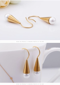 Detailed view of gold cone earrings with white pearls hanging on a white ceramic cup