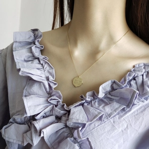 Close-up of a 925 sterling silver gold coin pendant necklace on a female model