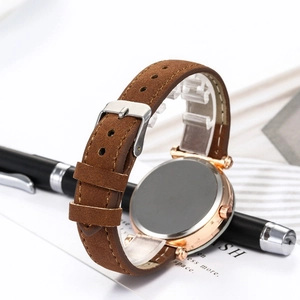 Detailed side view of rose gold watch case and brown suede leather strap with silver buckle