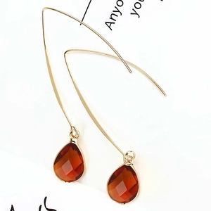Detail shot of faceted amber crystal teardrop earrings with golden long hook dangles