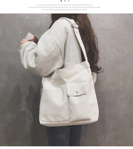 Zijaanzicht van beige canvas crossbodytas met brede schouderband en voorzak met flap