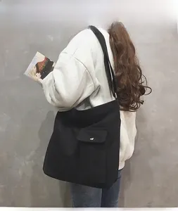 Detail van grote zwarte canvas tas met voorflapzak gepresenteerd door een model