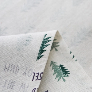 Macro shot of beige linen Christmas curtain fabric with green tree patterns and text