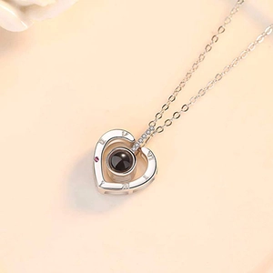 Detailed view of silver heart pendant featuring black projection stone and pink gemstone