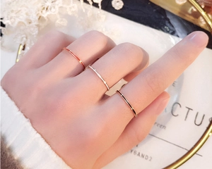 Close-up of three 1mm minimalist rose gold, silver, and gold thin rings on a model hand