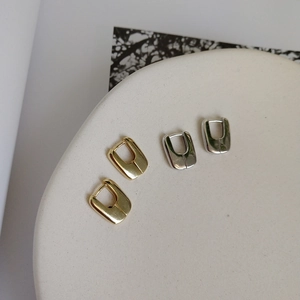 Detail of gold and silver U-shaped geometric earrings with polished mirror finish